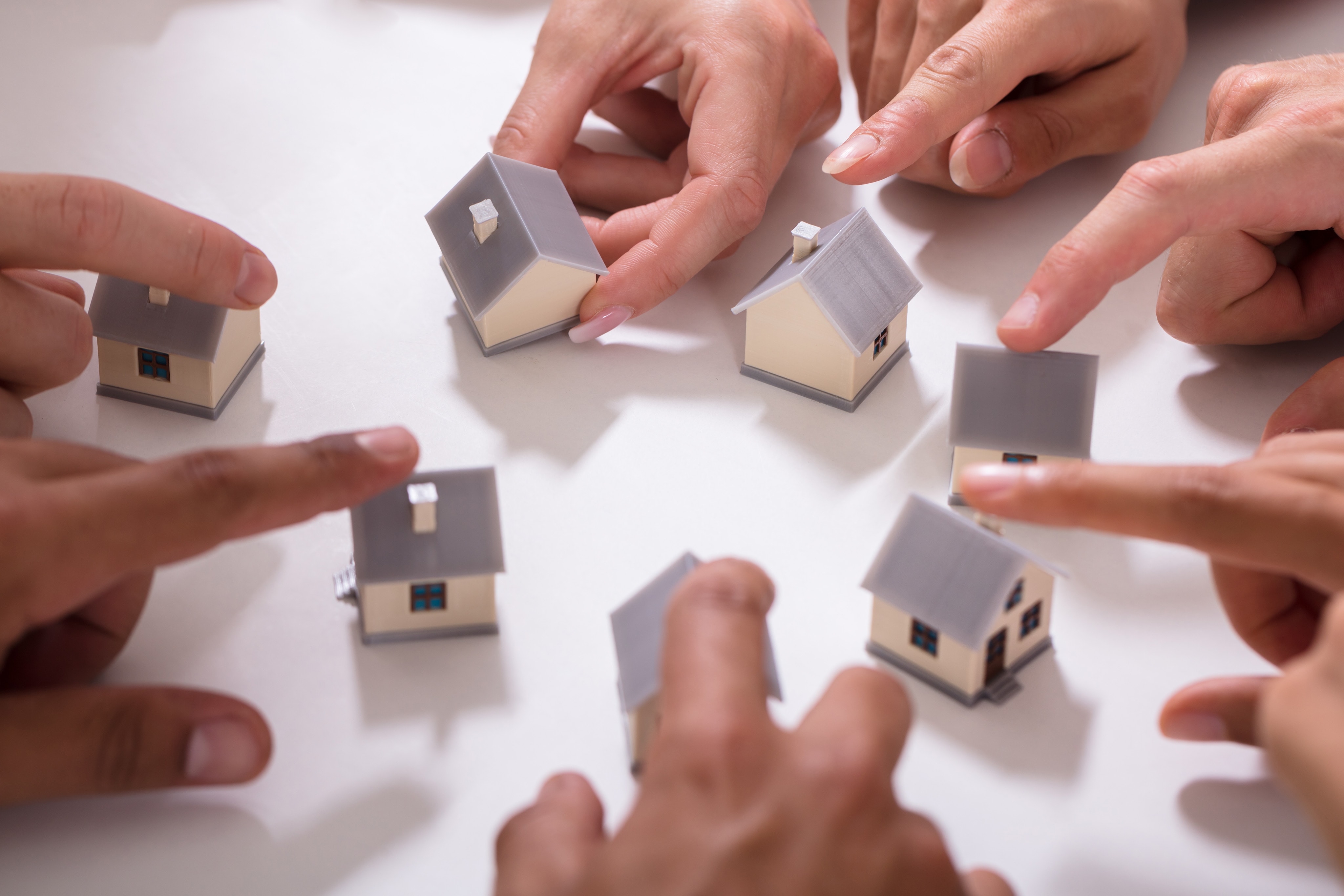 small house models with people touching them with their fingers