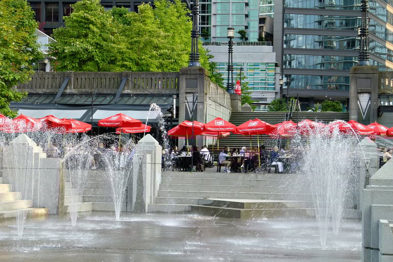 water fountain with people sitting behind it with red umbrellas