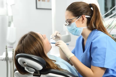 demale dentist inspecting a patients mouth