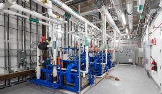 Chilled cold-water system with blue pipework and chiller equipment in a commercial plant room.