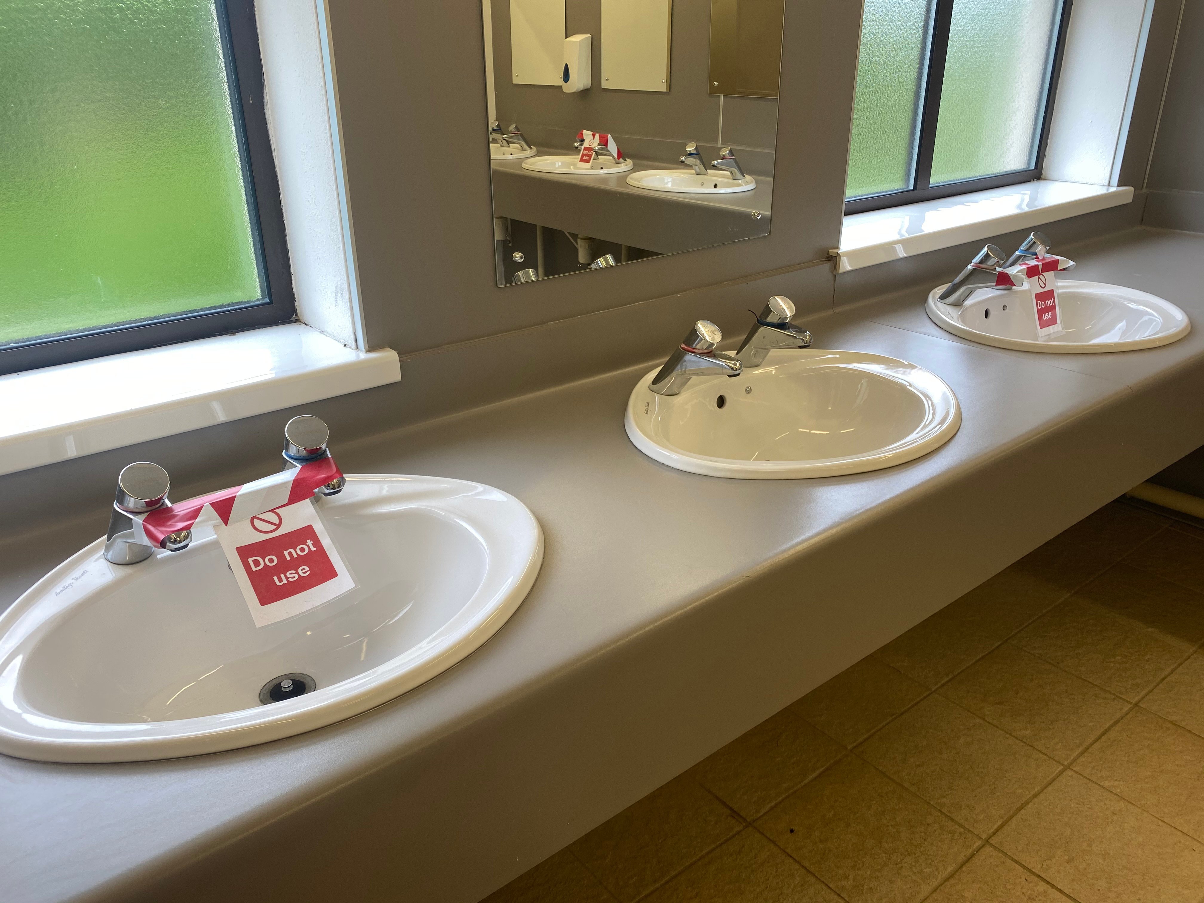 public toilet sinks  with warnings one them saying 'Do not use'