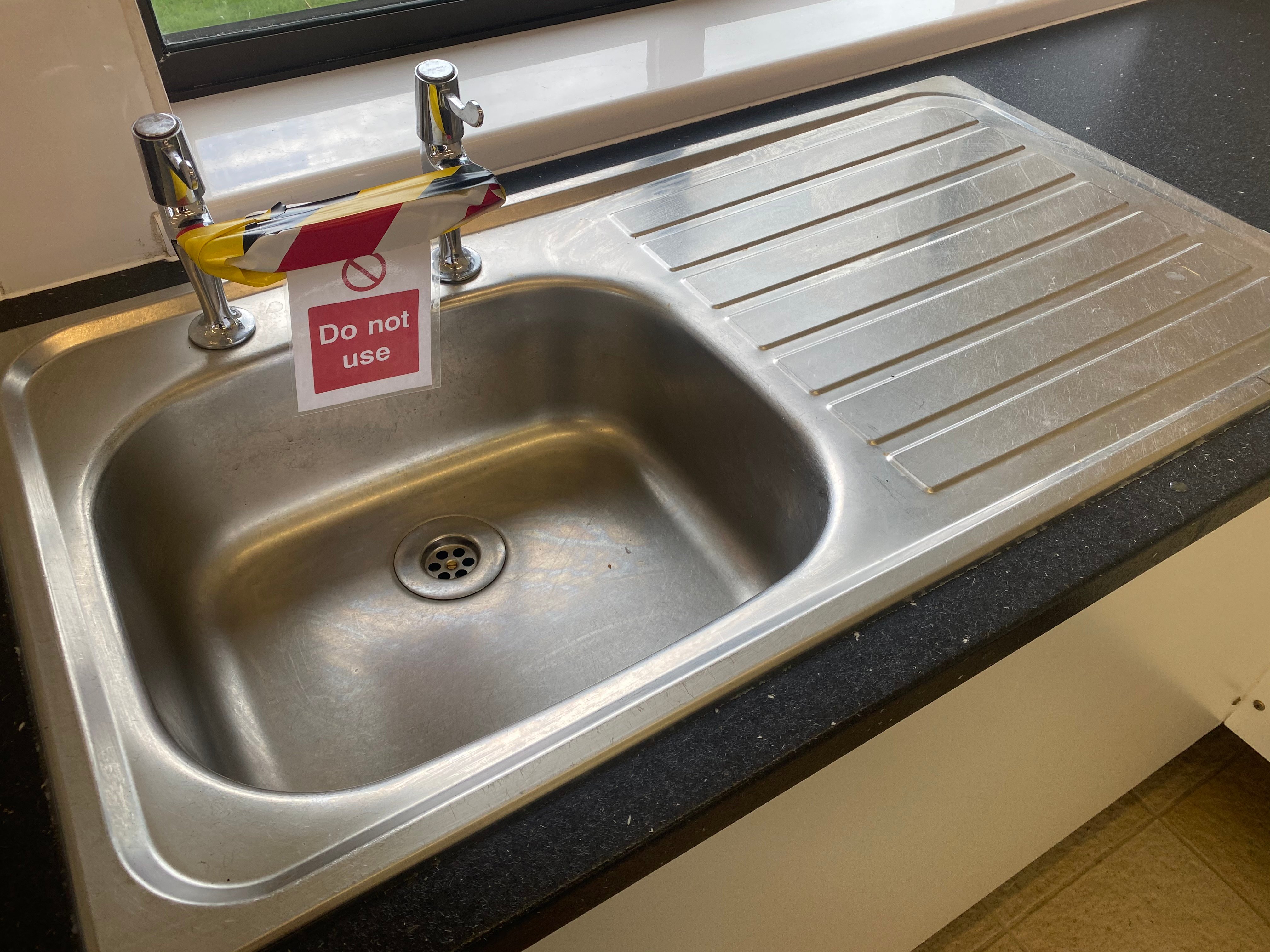 Sink with a sign on the taps saying 'do not use' during lockdown