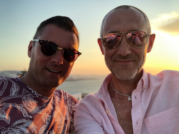 daniel pitcher in pink shirt with husband mark  on holiday with sunglasses on