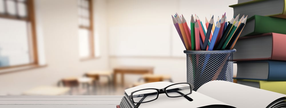 School supplies on desk against empty classroom