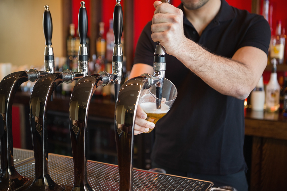 male Bar man pulling a pint of beer behind the bar