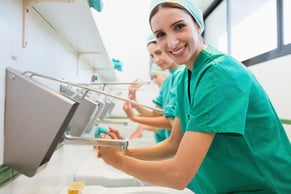 Surgeons washing their hands in a hospital while smiling