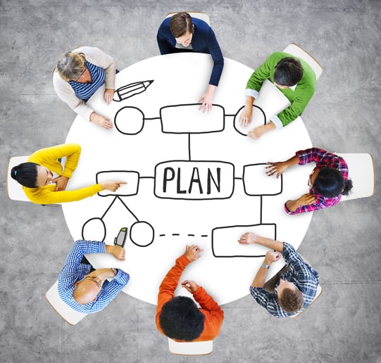 people sitting around a table with a plan