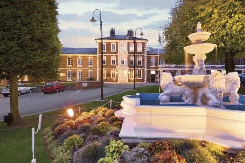 stone fountain in front of a grand house